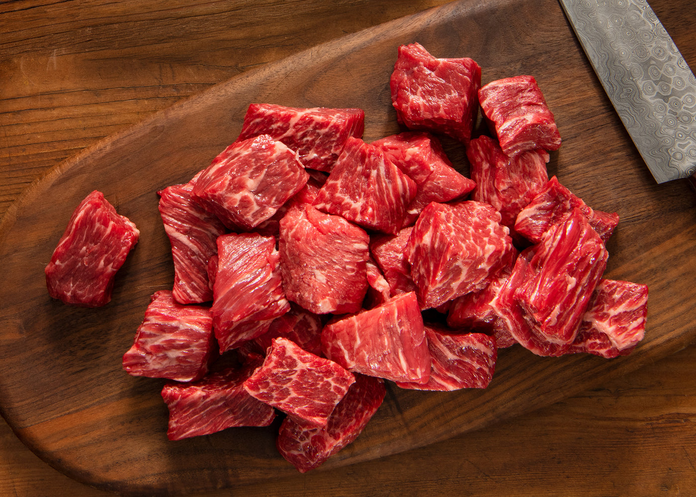 Premium steak bites on a wooden cutting board with a knife.